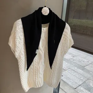 Detail shot of a soft white cable-knit short sleeve top paired with a black triangular scarf.