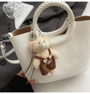 Weiße PU-Leder Eimer Handtasche mit geflochtenem Griff und süßem Teddybär Plüsch-Anhänger.