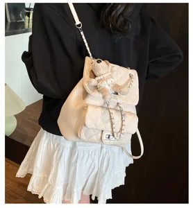 Détail de mini sac à dos matelassé avec bandoulière chaîne élégante et charmant pendentif.