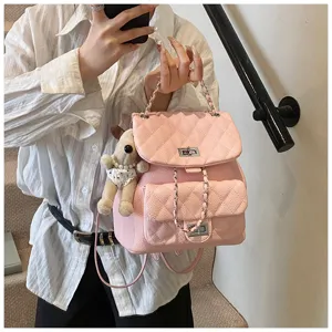 Détail sac à dos en cuir matelassé rose, bandoulière chaîne, fermoir tournant, charm peluche.