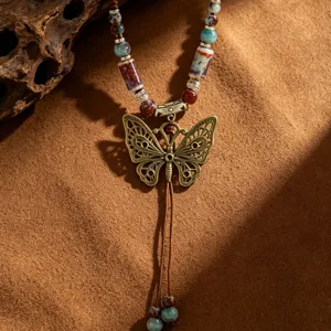Λεπτομέρεια μακρύ boho κολιέ με πολύχρωμες κεραμικές χάντρες και vintage μενταγιόν πεταλούδα.