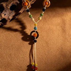 Κοντινό πλάνο boho κολιέ με κεραμικές χάντρες και ξύλινους κρίκους χειροποίητη υφή λεπτομέρειες.