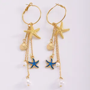 Detailed view of gold starfish and shell tassel earrings with blue enamel and pearls.