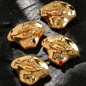 Nahaufnahme kreativer goldener Lippenbroschen mit Piercing-Stiften und funkelnden Kristallen.