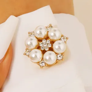 Close-up detail of a delicate pearl and crystal flower brooch collar pin, elegant gold tone.