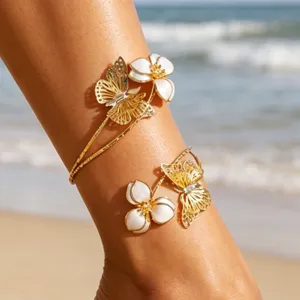 Gros plan d'une chevillère ouverte dorée ornée de fleurs en émail blanc et de papillons.