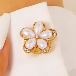 Close-up shot of the exquisite gold-tone pearl flower collar button with crystal details.