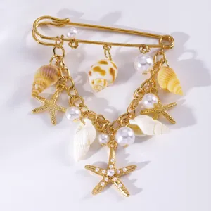 Spilla di sicurezza dorata con ciondoli a forma di conchiglia stella marina e perla donna.