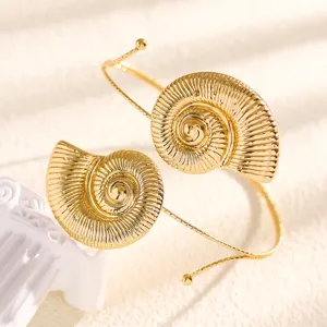 Close-up shot of gold ammonite conch shell open arm cuff bracelet, exquisite beach vacation jewelry detail.