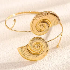 Gold conch shell arm bracelet detail shot, elegant beach vacation style accessory for women.