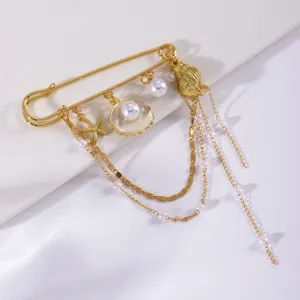 Primo piano della spilla di sicurezza dorata con ciondoli di perle conchiglie stelle.