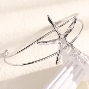 Close-up detail of silver starfish open arm cuff bracelet, beach vacation style jewelry for women.