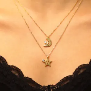 Gros plan de chaîne de clavicule double couche avec pendentifs lune et étoile en zircone.