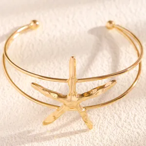 Close-up of gold starfish arm cuff detail, beach vacation style double-band adjustable bracelet.