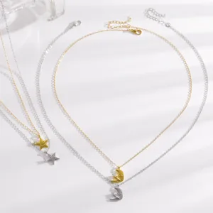 Gros plan sur les colliers superposés en or et argent avec pendentifs lune étoile zircon.