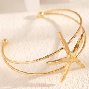 Gold starfish arm cuff detail, beach vacation open bracelet, marine style jewelry for women.