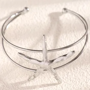Close-up view of a silver starfish arm cuff, showcasing metallic detail and texture.