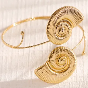 Gold nautilus arm cuff detail, beach vacation open bracelet, stylish ocean jewelry piece.