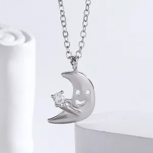 Gros plan détail du collier pendentif lune souriante en argent avec zircon scintillant.