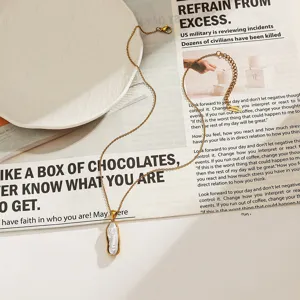 Gros plan d'un collier en acier inoxydable doré avec pendentif perle irrégulière.