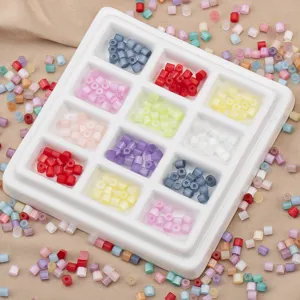 Close-up detail of colorful macaron glass seed beads arranged in a white divided storage tray.