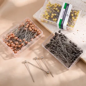 Stainless steel dressmaker pins with round ball heads in clear storage boxes for sewing crafts.
