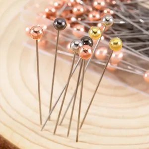 Close-up detail of colorful round head pearl pins and stainless steel sewing needles.
