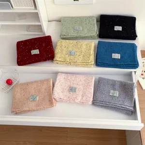 Detailed view of colorful speckled knit winter scarves for women, soft wool blend fabric.