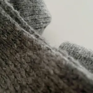 Grey knit scarf detail, soft wool texture close-up for autumn and winter cold weather warmth.
