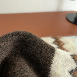 Close-up detail of cozy knit scarf texture, showing soft wool fuzziness and warm pattern.