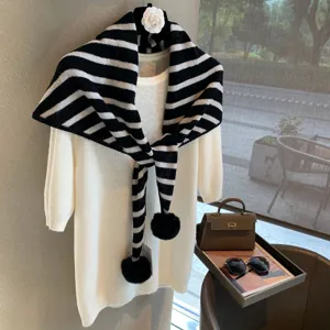 Classic black and white striped knitted triangular scarf with fluffy pom-poms for winter.