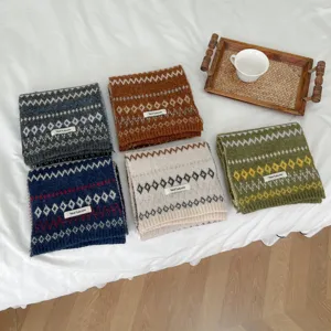 Detailed shot of cozy Fair Isle knit scarves in multiple colors neatly displayed on bed.