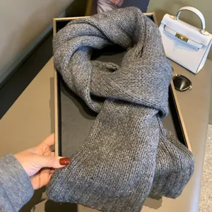 Cozy grey knitted winter scarf detail view, soft warm wool texture for cold weather wear.
