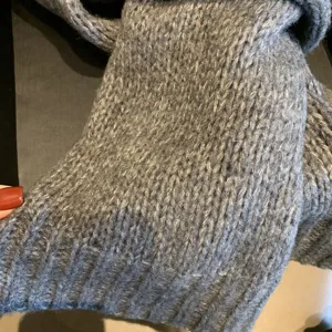 Closeup view of a grey knitted scarf showing soft wool texture and warm winter knit fabric details.