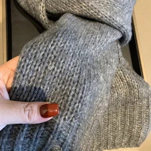 Close-up detail of a cozy grey knitted winter scarf, soft wool texture for warmth and style.