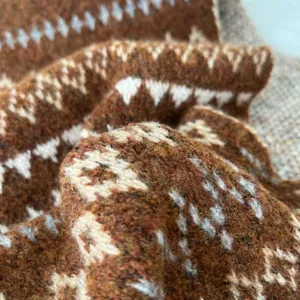 Close-up detail of cozy wool blend knit scarf featuring classic Fair Isle pattern texture.