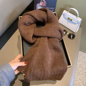 Detail shot of a cozy brown knitted scarf displayed in a tray, highlighting soft winter texture.