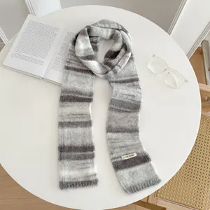 Detail shot of a retro knitted scarf featuring cozy grey and white gradient stripes.
