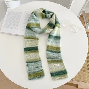 Close-up detail of the green gradient knit scarf featuring soft wool blend texture and cozy winter styling.