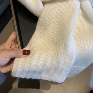 Detailed shot of a soft white knitted scarf showing cozy texture and ribbed hem design.