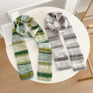 Close-up detail shot of retro color-block knitted striped scarves in green and grey on white table.