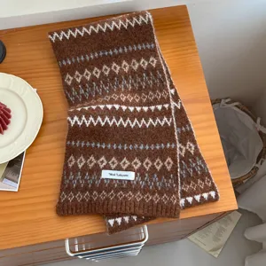 Detailed shot of a cozy brown Fair Isle knitted scarf featuring geometric patterns and a woven label.