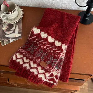 Gros plan détaillé d'une écharpe d'hiver rouge en tricot avec de jolis motifs de cœurs et flocons.