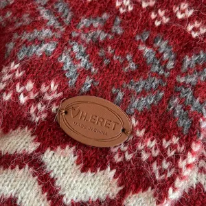 Vue détaillée d'écharpe en tricot nordique confortable avec motif flocon et patch en cuir.