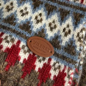 Detailed view of winter retro Fair Isle knit scarf featuring soft cozy texture and leather tag.