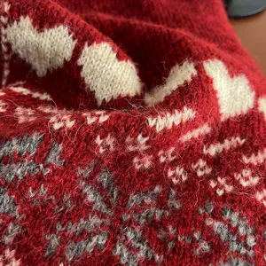 Gros plan sur la texture du tissu d'une écharpe d'hiver avec motifs de cœurs et flocons.