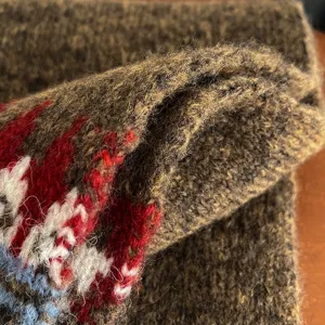 Close-up detail shot showing the cozy texture of a retro Fair Isle knit winter scarf.
