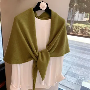 Green knitted shawl paired with white t-shirt, stylish and cozy women autumn winter apparel.