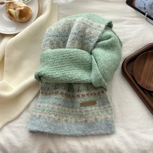 Close-up detail of the green Fair Isle knitted scarf, cozy winter texture and brand tag.