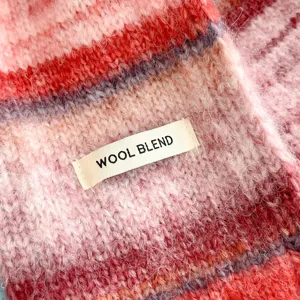 Close-up detail of the colorful knitted scarf showing soft wool blend texture and stripes.